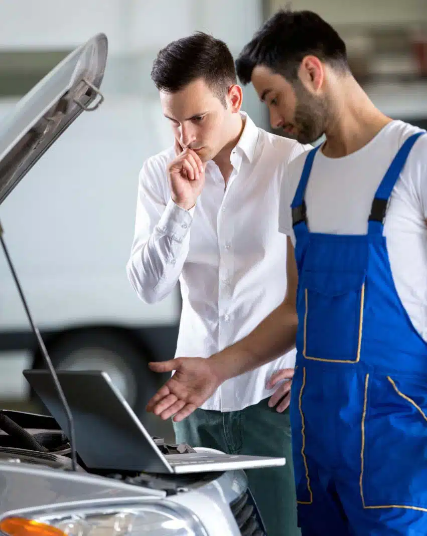 un mécanicien et un client étudie un litige de mécanique sur le moteur d'une voiture